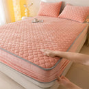 A close-up image of a quilted fleece mattress cover being fitted on a bed by a person's hand.