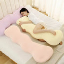 Woman lying on a U-shaped body pillow in a bedroom setting